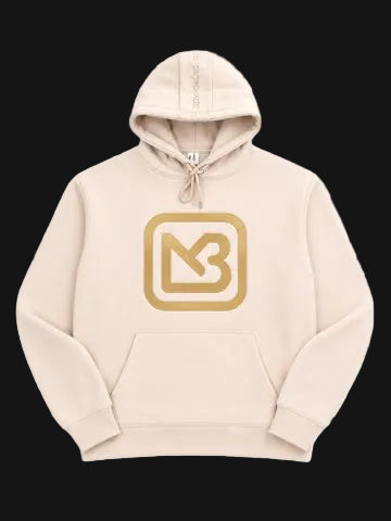 A light beige pullover hoodie with a large gold 'MB' logo inside a rounded square on the chest, displayed on a clean white background.